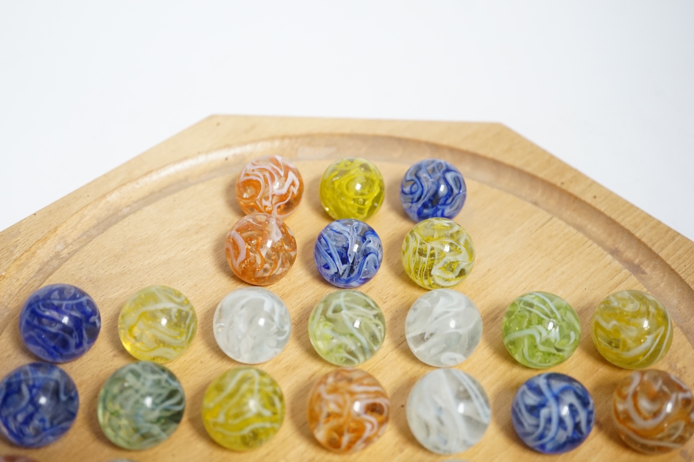 A turned wood solitaire board with multi-coloured glass marbles, 27cm wide